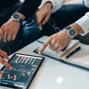Two businessmen discussing financial data on a tablet during a meeting.